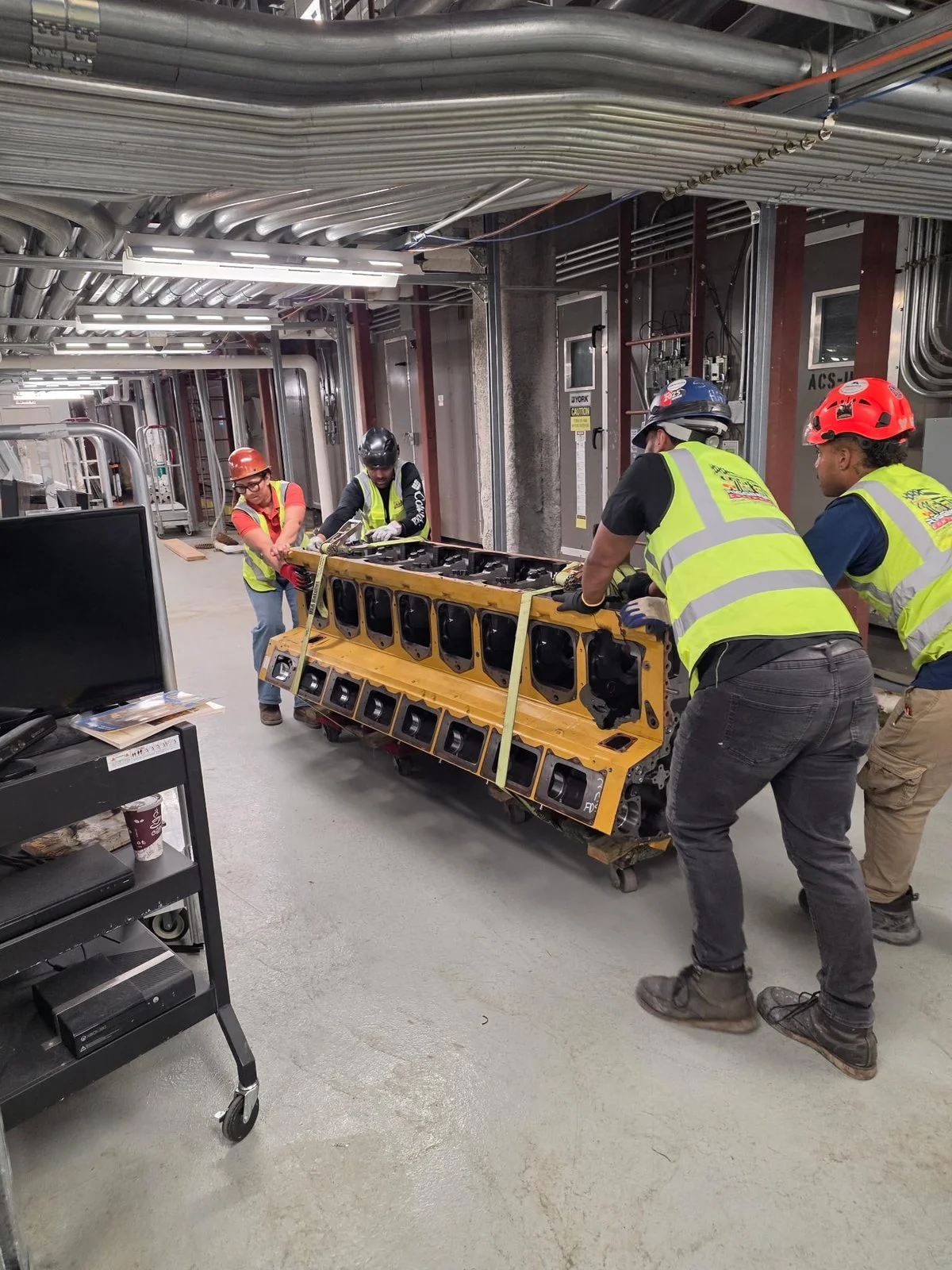Rigging NYC Contractors crew skating heavy plant equipment through a tight mechanical room in New York